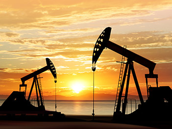 Oil drilling rigs with sunset and ocean